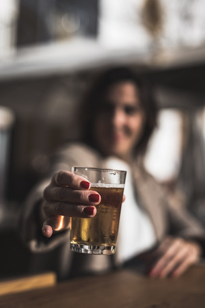 40 year old woman drinking beer on the terrace of a backlit barの写真素材