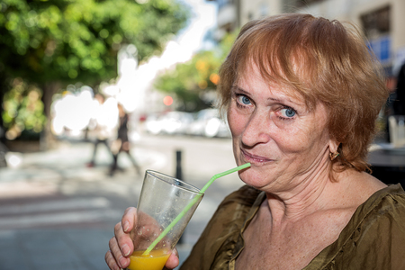 Senior woman eating on the terrace of a restaurant outsideの写真素材