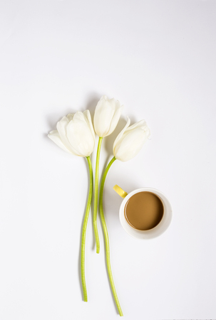 Floral background with red and white tulips and coffee, and green leaves on white background. Flat lay, top viewの写真素材