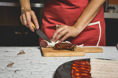 Unrecognizable woman cutting sausages and preparing a saladの写真素材