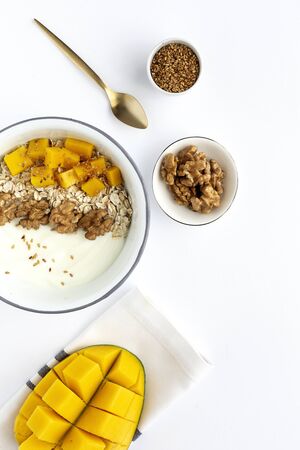 Bowl of homemade granola with yogurt and cereals and mango fruit and walnuts on white background from top view. Healthy food From above. Flat layの写真素材