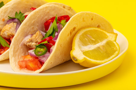 Homemade Mexican Tacos with fresh vegetables and chicken on yellow background. Healthy food...