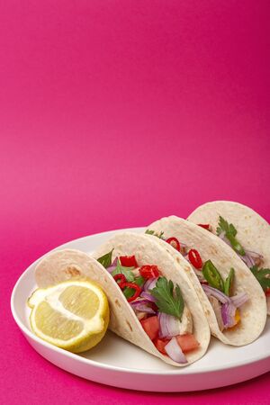 Homemade Mexican Tacos with fresh vegetables and chicken on fucshia background. Healthy food .Burritos. Isolatedの写真素材
