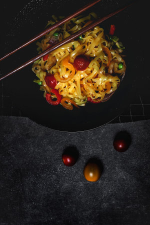 Vegan noodles with peas, peppers, onion and zucchini on dark background. Healthy food. Asian foodの写真素材
