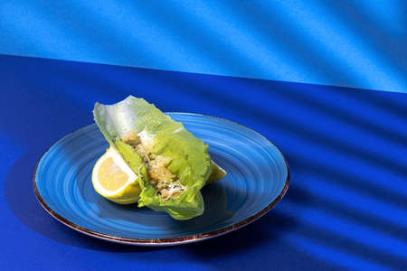 Homemade Caesar salad with chicken, lettuce, lemon, toast, caesar sauce, cheese and garlic.On blue background.Healthy food conceptの写真素材
