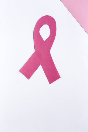 Pink ribbon on a colored background from above. Cancer disease. Flat lay