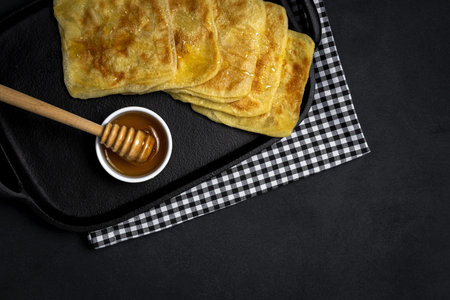 Homemade and traditional Arabic rghaif or msemen with honey and cream cheese on dark background....
