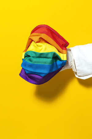 hands with gloves showing homemade fashion and design LGBT masks for covid-19 protection on colored backgroundsの写真素材
