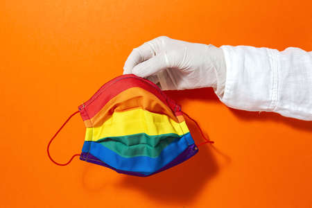 hands with gloves showing homemade fashion and design LGBT masks for covid-19 protection on colored backgroundsの写真素材