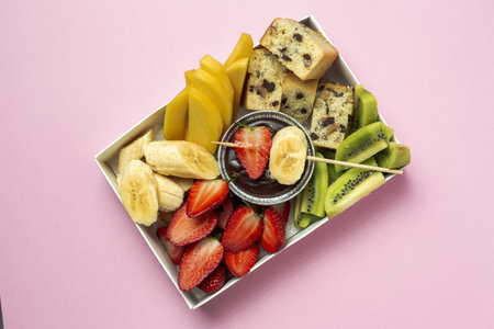 Box of fruits with chocolate ready to eat, take away. Strawberries; mango; banana; Kiwi; Biscuit. Delivery concept. Healthy foodの写真素材