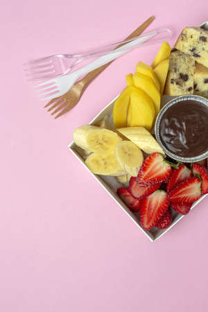 Box of fruits with chocolate ready to eat, take away. Strawberries; mango; banana; Kiwi; Biscuit. Delivery concept. Healthy foodの写真素材