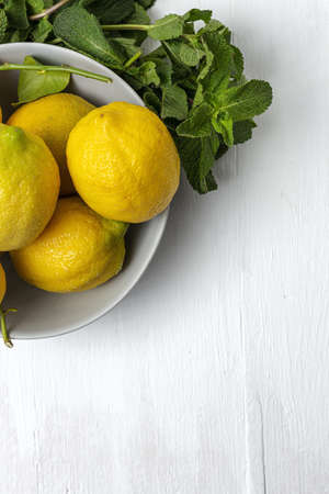 Fresh lemons with green mint leaves on white background from above. Flat layの写真素材