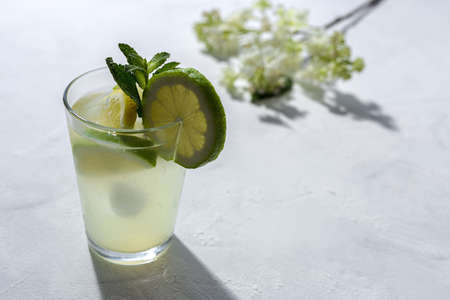 Refreshing homemade glass lemonade with ice and mint in sunlight on white backgroundの写真素材