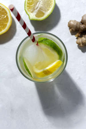 Refreshing homemade glass lemonade with ice and mint in sunlight on white backgroundの写真素材