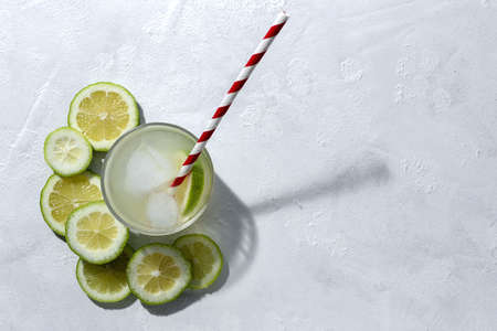 Refreshing homemade glass lemonade with ice and mint in sunlight on white backgroundの写真素材