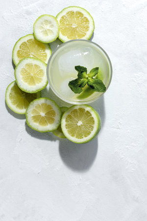 Refreshing homemade glass lemonade with ice and mint in sunlight on white background