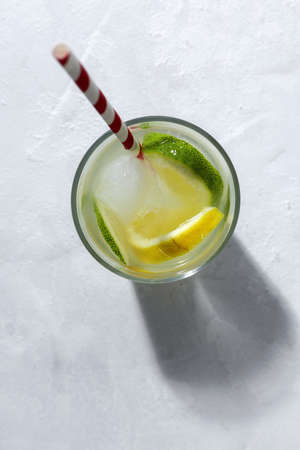 Refreshing homemade glass lemonade with ice and mint in sunlight on white backgroundの写真素材