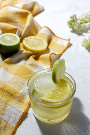 Refreshing homemade glass lemonade with ice and mint in sunlight on white backgroundの写真素材