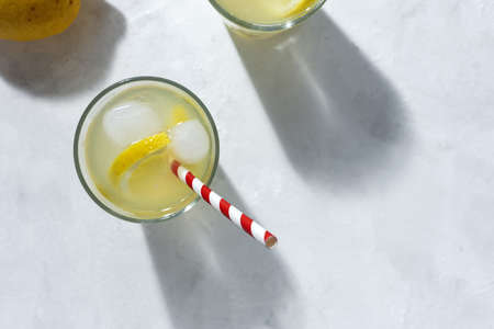 Refreshing homemade glass lemonade with ice and mint in sunlight on white backgroundの写真素材
