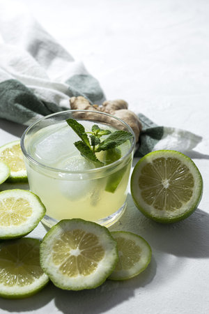 Refreshing homemade glass lemonade with ice and mint in sunlight on white backgroundの写真素材