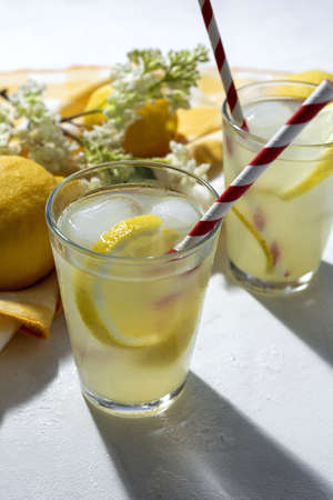 Refreshing homemade glass lemonade with ice and mint in sunlight on white backgroundの写真素材
