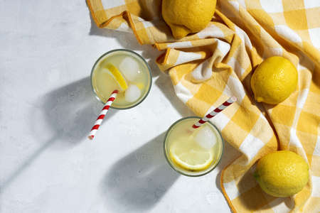 Refreshing homemade glass lemonade with ice and mint in sunlight on white backgroundの写真素材