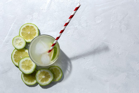 Refreshing homemade glass lemonade with ice and mint in sunlight on white background