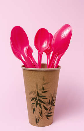 Plastic disposable tableware, forks, spoons, glasses on pink background. Caring for the environment. The problem is recycling. Reuse. Place for text.の写真素材