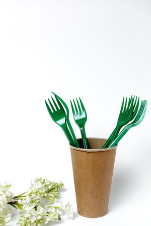 Plastic disposable tableware, forks, spoons, glasses on white background. Caring for the...