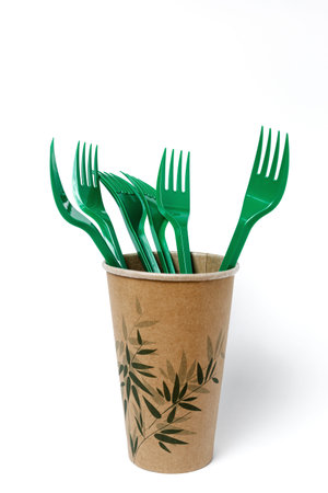 Plastic disposable tableware, forks, spoons, glasses on white background. Caring for the...