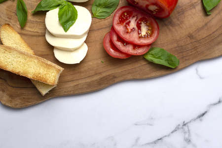 Homemade Italian caprese salad with sliced tomatoes, mozzarella cheese, basil, olive oil and salt.の写真素材