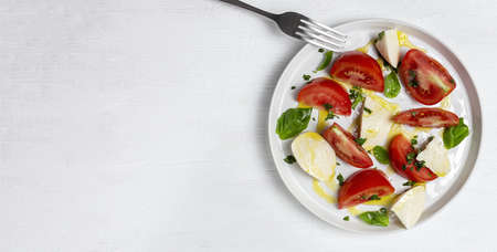 Homemade Italian caprese salad with sliced tomatoes, mozzarella cheese, basil, olive oil and salt.の写真素材