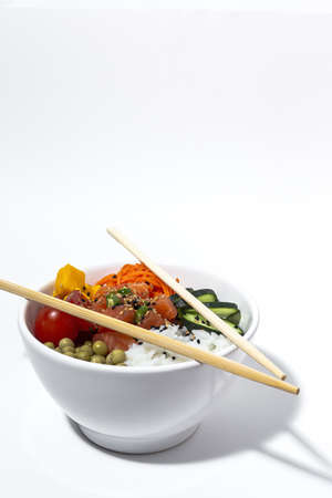 Traditional homemade asian salmon poke bowl with peas, rice; carrot, cucumber, cherry tomatoes, mango and sesame seeds.の写真素材