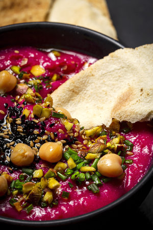 Homemade Beet and Chickpea Hummus with Vegetable CruditÃ©s and Unleavened Bread on Dark Background
