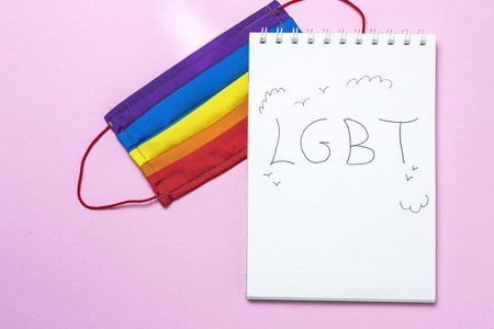 LGBT background with rainbow colored protective face mask from above. Flat lay.