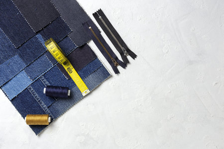 Handicraft, clothing repair. Ripped blue jeans sewing accessories from above. Flat lay