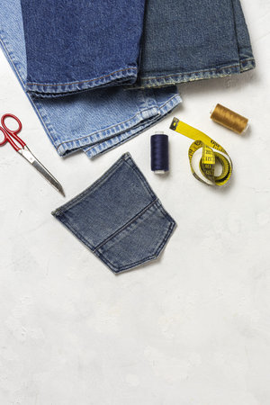 Handicraft, clothing repair. Ripped blue jeans sewing accessories from above. Flat lay