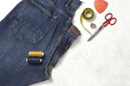 Handicraft, clothing repair. Ripped blue jeans sewing accessories from above. Flat layの写真素材