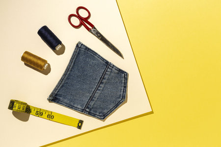 Handicraft, clothing repair. Ripped blue jeans sewing accessories with colorful background from...