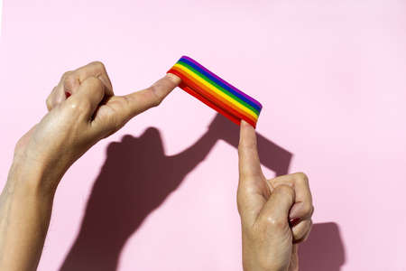 Woman hands with LGBT bracelet on pink backgroundの写真素材