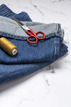 Handicraft, clothing repair. Ripped blue jeans sewing accessories with colorful background from above. Flat layの写真素材