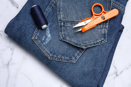 Handicraft, clothing repair. Ripped blue jeans sewing accessories with colorful background from...