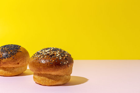Assorted round homemade brioche buns with seeds on a colorful background with high contrast lightの写真素材