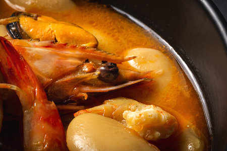 Homemade bean stew with prawns and mussels on dark background. Typical Spanish food