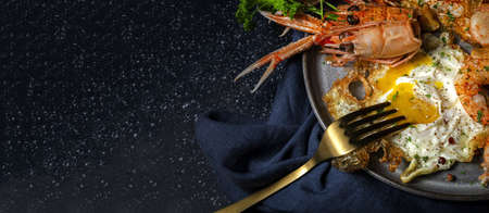 Homemade Fried Eggs with Prawns, Langoustines, Prawns, Garlic and Spices on Dark Background. seafood conceptの写真素材