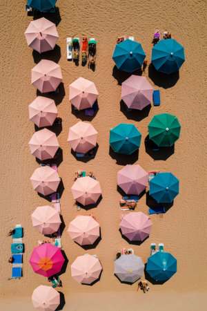 Generative AI illustration of Colorful beach umbrellas on a sunny day from above view. holidays conceptの素材