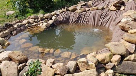 finishing a pond in the garden, surrounded by stones to make a natural pond.の写真素材