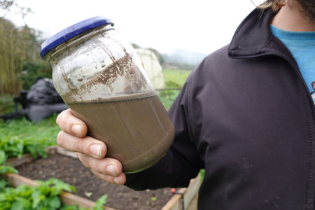 gardener holds jar of bleach ash for use in the vegetable garden as fertilizer and insecticide.の写真素材