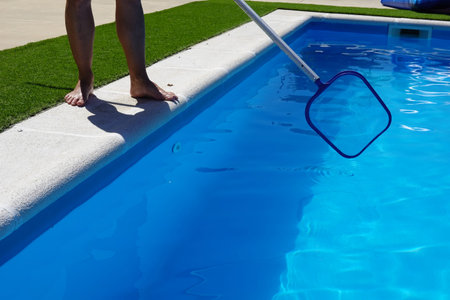 man cleaning the pool surface with pool cleaner mesh or skimmer