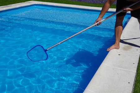 man cleaning the pool surface with pool cleaner mesh or skimmerの写真素材